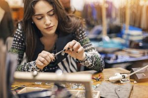 Young woman creating handmade jewelry in her studio